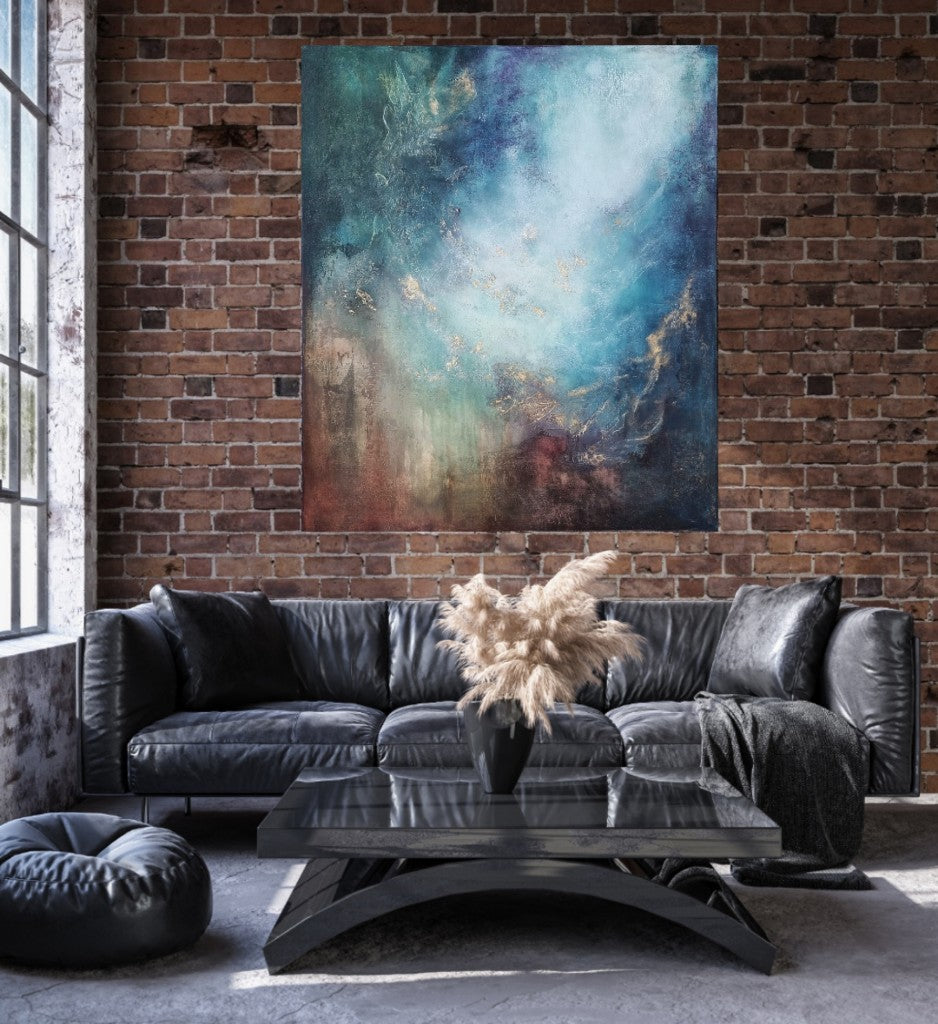 Large colorful artwork on an old brick wall in the loft-style living room above a gray leather couch.