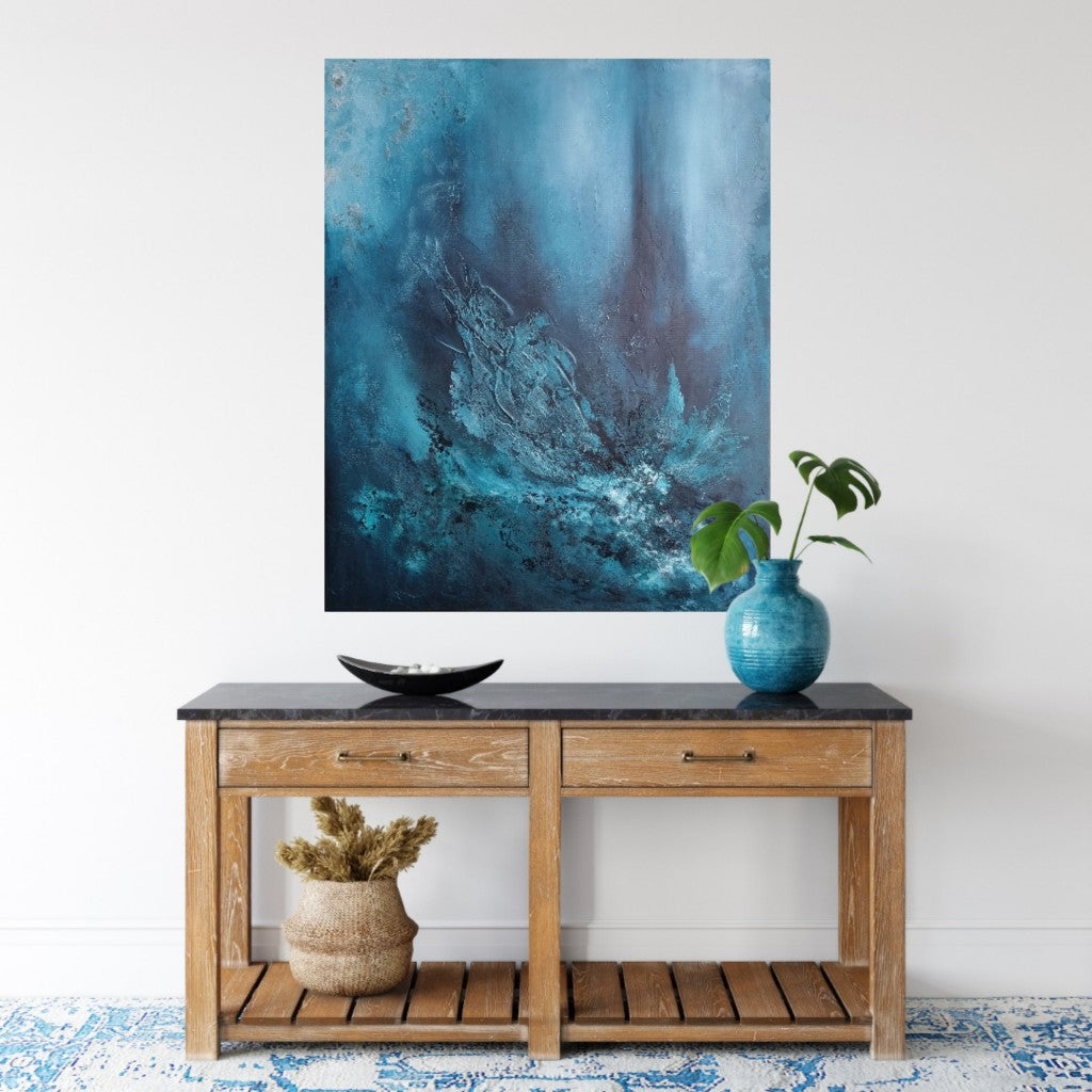 Large abstract painting with texture and shades of blue, green and petrol  above a wooden  sideboard.