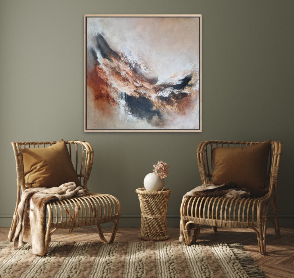 Large abstract acrylic painting with warm autumn colors. In a scandi-boho style living room above 2 wooden armchairs.