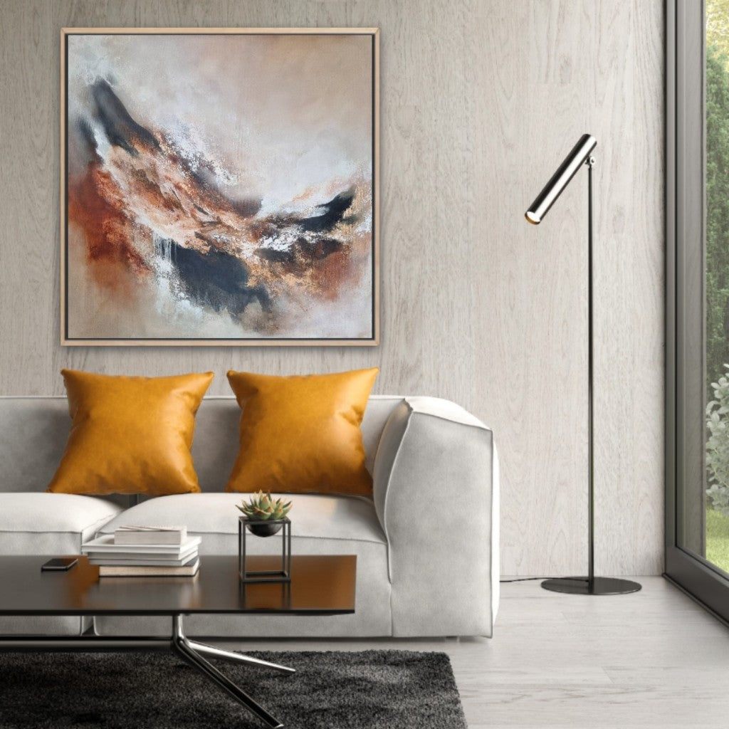 Large abstract acrylic painting with warm autumn colors. In a modern style living room on the gray wall above a gray sofa with 2 orange pillows.