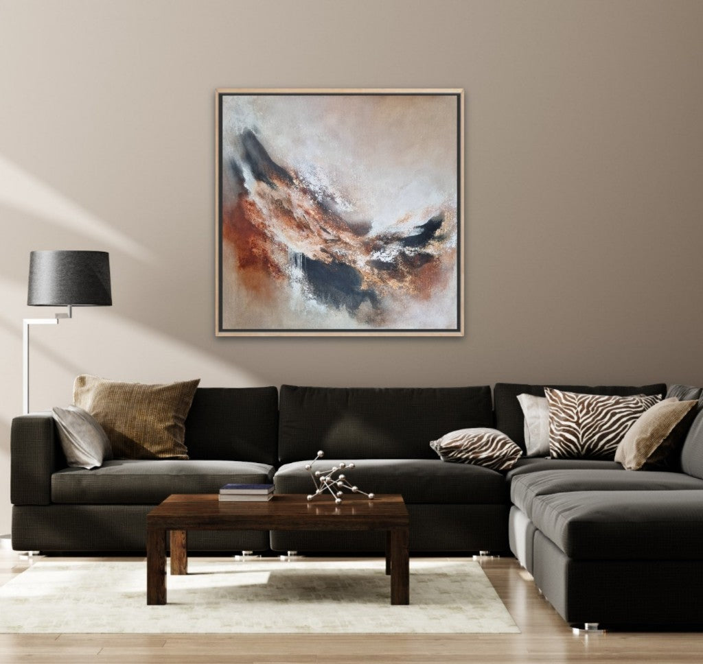 Large abstract acrylic painting with warm autumn colors. In a modern living room with beige walls and a dark gray lounge sofa.